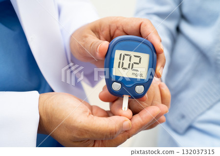 Asian doctor using digital glucose meter for check sample blood sugar level to treatment diabetes. Asian doctor using digital glucose meter for check sample blood sugar level to treatment diabetes. 132037315