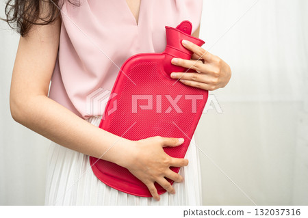 Woman using hot water bottle to relieve menstrual abdominal pain. 132037316