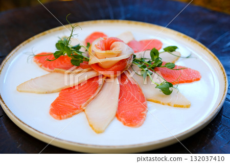 oily red fish in slices on a white plate Sashimi slices arranged on a floral-patterned porcelain plate, garnished with fresh wasabi and daikon strips for a refined presentation. oily red fish in slices on a white plate Sashimi slices arranged on a floral-patterned porcelain plate, garnished with fresh wasabi and daikon strips for a refined presentation. 132037410