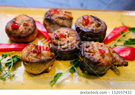mackerel rolls healthy baked fillet of mackerel in rolls slices on white dish on cutting board with fork and knife, spices and plate with cherry tomatoes on background, close-up mackerel rolls healthy baked fillet of mackerel in rolls slices on white dish on cutting board with fork and knife, spices and plate with cherry tomatoes on background, close-up 132037432