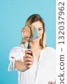 Studio portrait of woman with magnifying glass 132037962