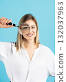Studio portrait of woman with magnifying glass 132037963