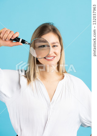 Studio portrait of woman with magnifying glass 132037963