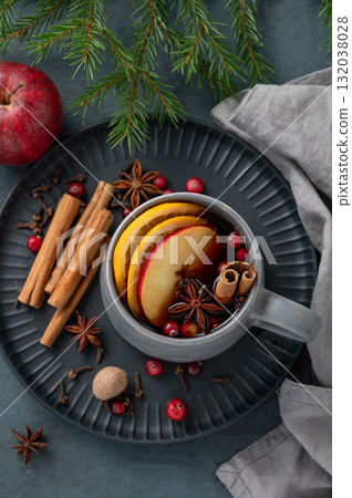 A cup of red mulled wine with spices, orange, apple slices and cranberry on a dark background 132038028