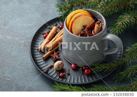 A cup of red mulled wine with spices, orange, apple slices and cranberry on a dark background A cup of red mulled wine with spices, orange, apple slices and cranberry on a dark background 132038030