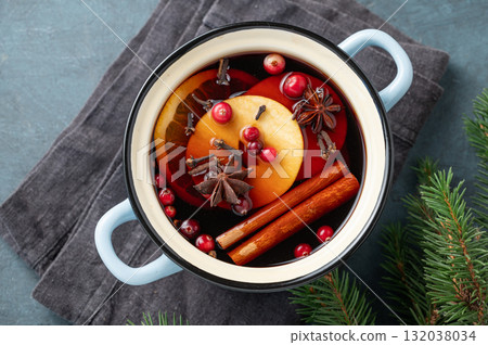 A pot of red mulled wine with spices, orange, apple slices and cranberries on a dark blue background A pot of red mulled wine with spices, orange, apple slices and cranberries on a dark blue background 132038034