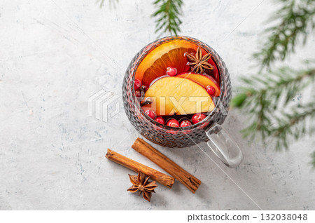 A cup of red mulled wine with spices, orange and apple slices on a light background with cinnamon A cup of red mulled wine with spices, orange and apple slices on a light background with cinnamon 132038048