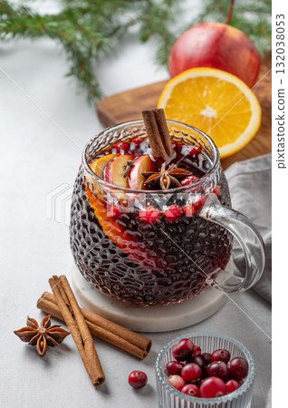 A cup of red mulled wine with spices, orange and apple slices on a light background 132038053