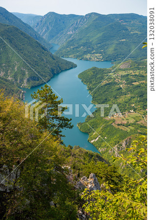 Canyon river meandering among green forested mountains, nature landscape photography under blue sky 132038091