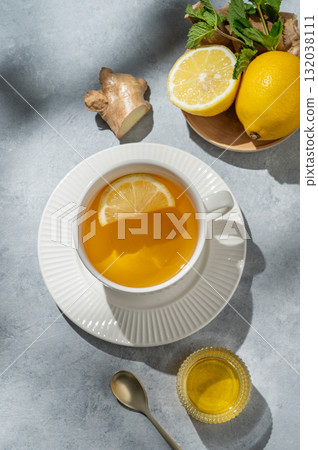 Hot tea with lemon, ginger, honey, and mint in a cup on a blue background with citrus fruits 132038111
