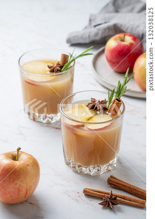 Two glasses of apple cider with cinnamon, anise, and rosemary on a marble background with fruits Two glasses of apple cider with cinnamon, anise, and rosemary on a marble background with fruits 132038125
