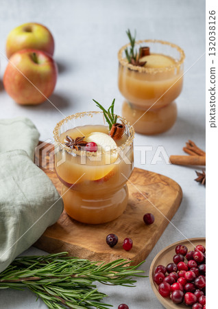 Apple cider with cinnamon, anise, brown sugar and rosemary on a wooden board on a light background Apple cider with cinnamon, anise, brown sugar and rosemary on a wooden board on a light background 132038126