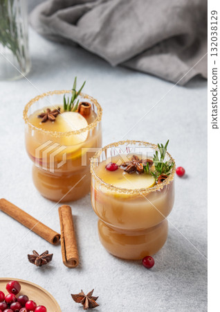 Two glasses of hot apple cider with cinnamon, anise, brown sugar and rosemary on a light background Two glasses of hot apple cider with cinnamon, anise, brown sugar and rosemary on a light background 132038129
