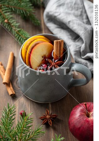 A cup of red mulled wine with spices, orange, apple slices and cranberry on a wooden background A cup of red mulled wine with spices, orange, apple slices and cranberry on a wooden background 132038136