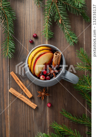 A cup of red mulled wine with spices, orange, apple slices and cranberry on a wooden background A cup of red mulled wine with spices, orange, apple slices and cranberry on a wooden background 132038137