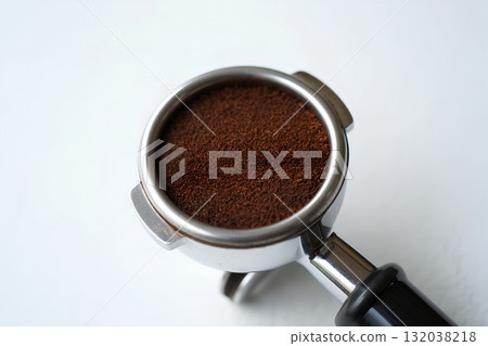 Freshly ground coffee packed into professional espresso machine portafilter, ready for brewing, isolated on white background 132038218