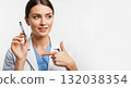 A female doctor holds and points to an insulin pen for diabetes treatment. Healthcare professional explaining a medical device on a white background with copy space 132038354