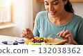 Diabetic woman eating a healthy breakfast of fruit and toast. Managing blood sugar with a balanced diet and glucometer. Healthy lifestyle and diabetes care concept 132038362
