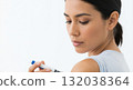 A young woman gives herself an insulin injection with a pen in her arm. Diabetic patient managing a chronic illness. Medical self-care concept with copy space 132038364