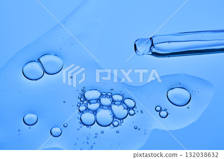 The texture of the facial serum on a blue background with pipettes. 132038632