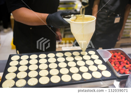 Pancake batter being poured onto a griddle at a busy kitchen in a food fair 132039071