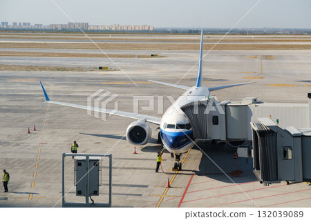 Plane docking at the airport gate with crew preparing for passenger boarding on a sunny afternoon 132039089