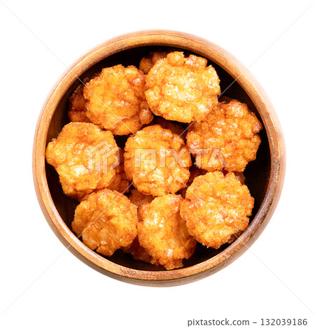 Thai chili rice crackers in a wooden bowl. Hot, sweet and spicy crispies, a snack made of rice, seasoned with chili powder and flavored with soy sauce. Close-up, from above, isolated over white. Photo 132039186