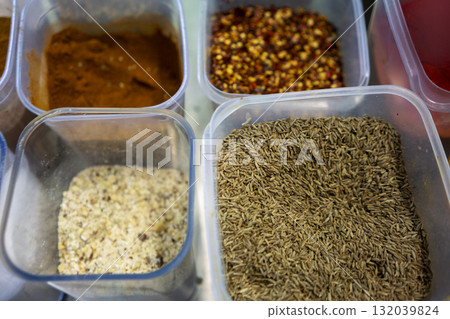 Indian spices filling plastic containers in a restaurant kitchen Indian spices filling plastic containers in a restaurant kitchen 132039824
