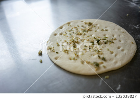 Preparing delicious naan bread with garlic and herbs in an indian restaurant 132039827