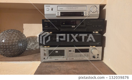 MADRID, SPAIN - AUGUST, 02, 2025. Retro home entertainment setup with vintage video recorders and electronics on shelf 132039876