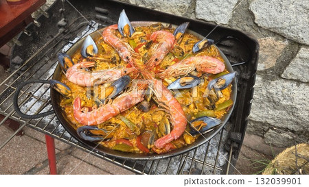 Traditional spanish paella with seafood on outdoor grill setting. Typical cuisine of Spain. Valencian cuisine. Stage of cooking paella. Ingredients for paella 132039901