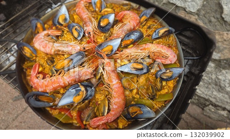 Traditional spanish paella with seafood including shrimp and mussels on rustic background. Typical cuisine of Spain. Valencian cuisine. Stage of cooking paella. Ingredients for paella 132039902