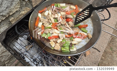 Traditional spanish paella cooking outdoors with fresh ingredients. Typical cuisine of Spain. Valencian cuisine. Stage of cooking paella. Ingredients for paella 132039949