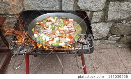 Traditional spanish paella cooking outdoors with seafood and vegetables. Typical cuisine of Spain. Valencian cuisine. Stage of cooking paella. Ingredients for paella 132039966