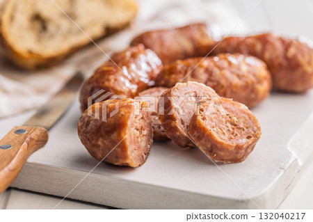 Photo of roasted italian sausage salsiccia on cutting board on white table. 132040217