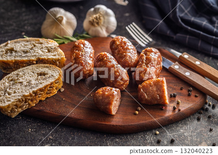 Photo of roasted italian sausage salsiccia on cutting board on black table. 132040223