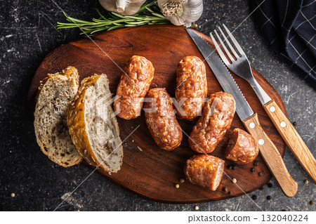 Photo of roasted italian sausage salsiccia on cutting board on black table. 132040224