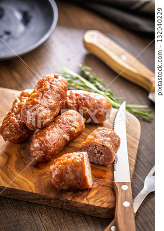 Photo of roasted italian sausage salsiccia on cutting board on wooden table. Photo of roasted italian sausage salsiccia on cutting board on wooden table. 132040229