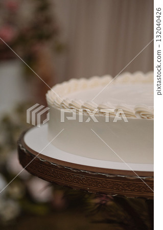 Close-up of white frosted cake on decorative stand with blurred background 132040426