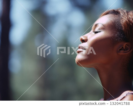 Girl enjoying deep breath in natural forest with green leaves and gentle glow. Health and tranquility shown in peaceful outdoor moment. 132041788