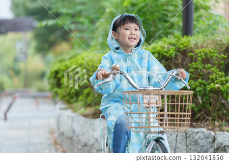 A child riding a bicycle in a raincoat on a rainy day A child riding a bicycle in a raincoat on a rainy day 132041850