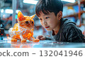 Young Boy Fascinated by Luminous Orange Cat Model in Tech 132041946