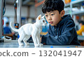 Fascinated young boy observes a 3D printed white cat model 132041947