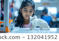 Young Asian girl fascinated by 3D printed cat in workshop 132041952