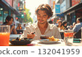 Young man enjoying an outdoor meal while using his smartphone. 132041959