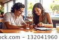 Young Couple Smiling While Using Mobile Payment Device at Cafe 132041960