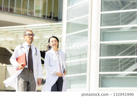 Men and women wearing white coats walking 132041990