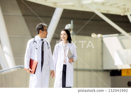 Men and women wearing white coats walking Men and women wearing white coats walking 132041992