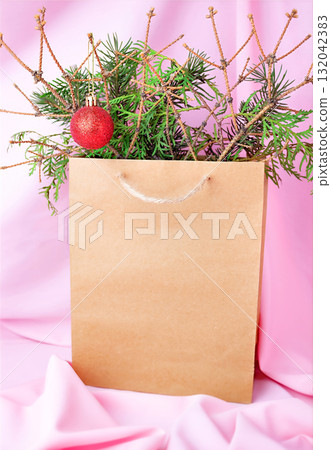 Christmas photo in a craft bag with fir branches on a pink fabric background 132042383