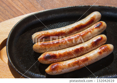Sausages grilled on an iron plate 132042619